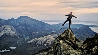 Scots Mountaineer TomMillar balancing on one leg at the summit of Sgurr nan Gillean