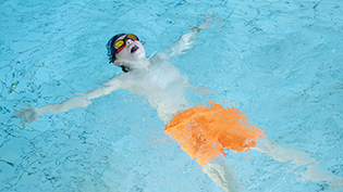 Boy practicing float technique in pool