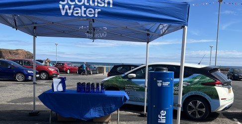 Set up of Top Up Tap launch including small gazebo, table offering reusable water bottles, and Scottish Water branded vehicle
