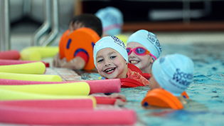 Learn to Swim Partnership 200K Milestone kid in swimming pool with floats