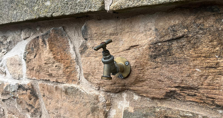 outdoor tap mounted on a stone wall